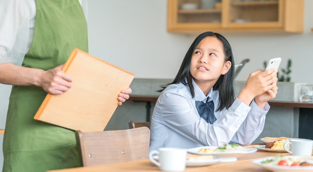 スマホをいじる女子高生
