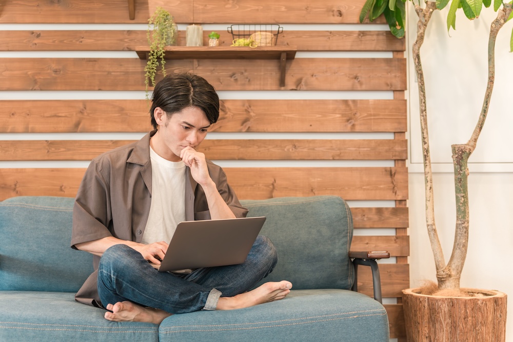 ソファーに座ってパソコンを睨む男性