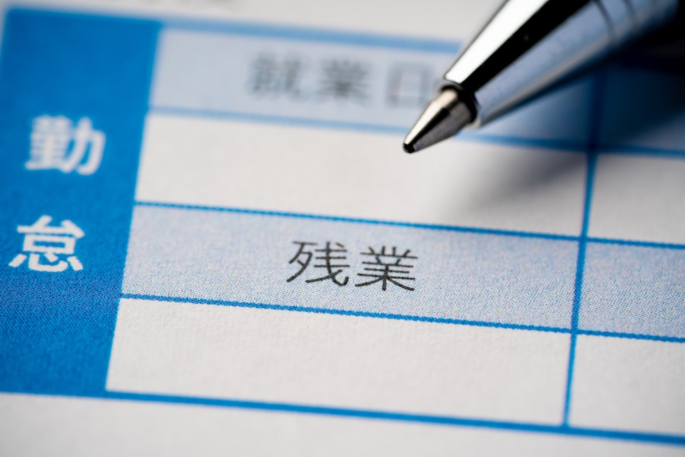 残業と書かれた紙を指すペン