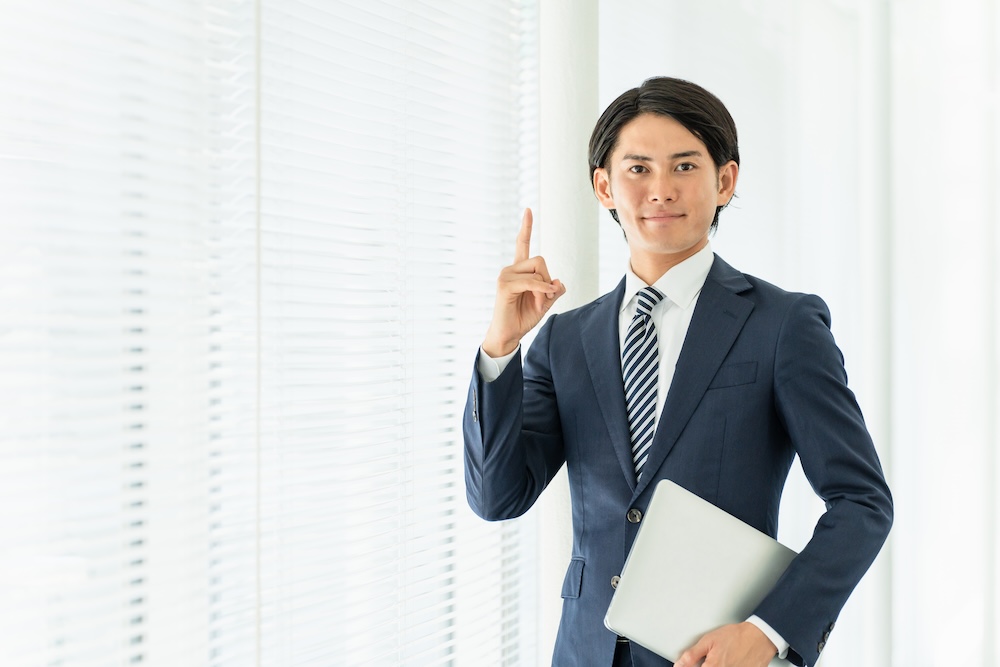 人差し指を立てているスーツの男性