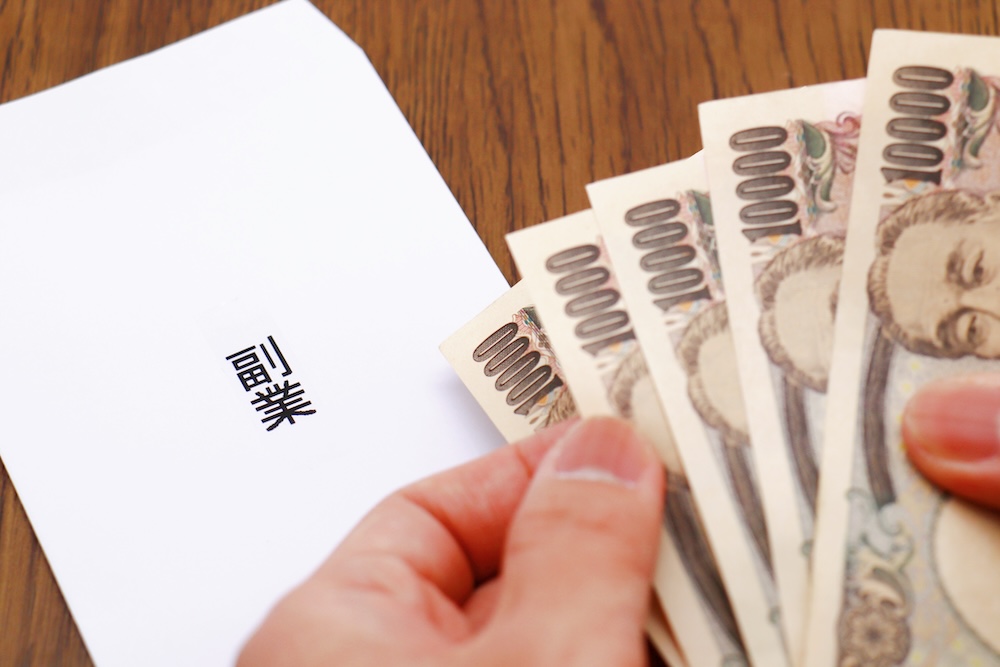 副業と書かれた封筒と1万円札を持つ